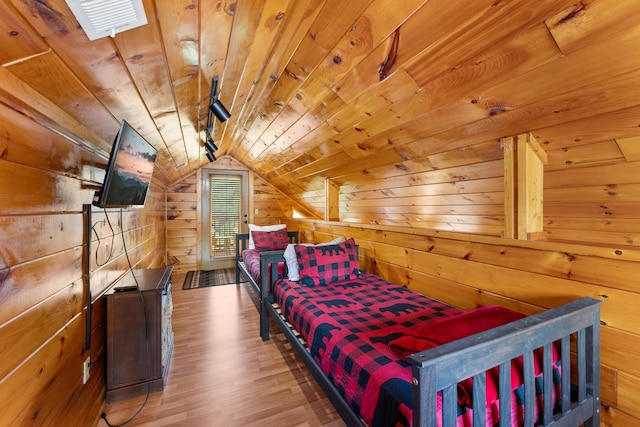 bedroom featuring lofted ceiling, wooden ceiling, wood walls, and wood finished floors