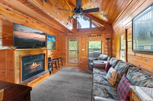 living area with vaulted ceiling, a warm lit fireplace, wood ceiling, and wood walls