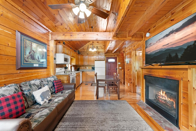 living room with light wood-style flooring, wood ceiling, and wooden walls