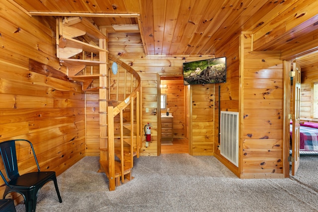 stairway with carpet, wood ceiling, wooden walls, and visible vents