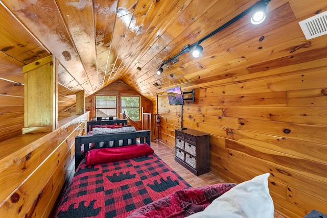 bedroom with visible vents, wood ceiling, vaulted ceiling, wooden walls, and wood finished floors