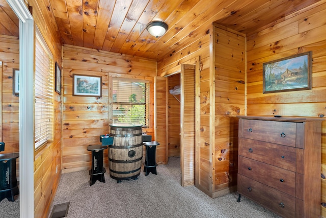 interior space featuring carpet, wood walls, wooden ceiling, and visible vents