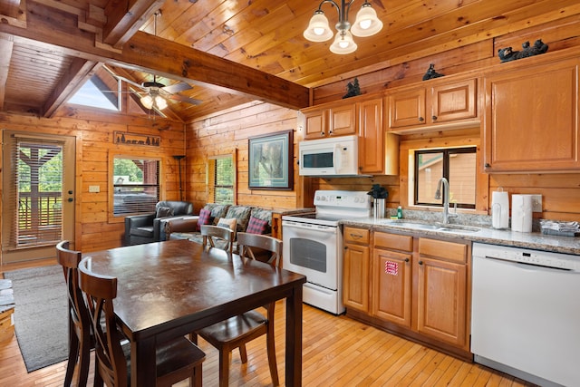 kitchen with vaulted ceiling with beams, light wood-style flooring, a sink, wood walls, and white appliances