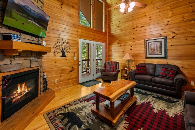 living room with a stone fireplace, ceiling fan, and light wood-type flooring