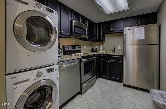 3215 N River Rd Unit 103, Pigeon Forge, TN 37863 - kitchen with appliances with stainless steel finishes, stacked washer / drying machine, dark cabinets, and light stone countertops