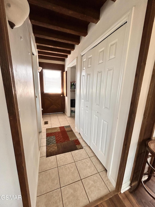 hallway featuring beam ceiling and light tile patterned flooring