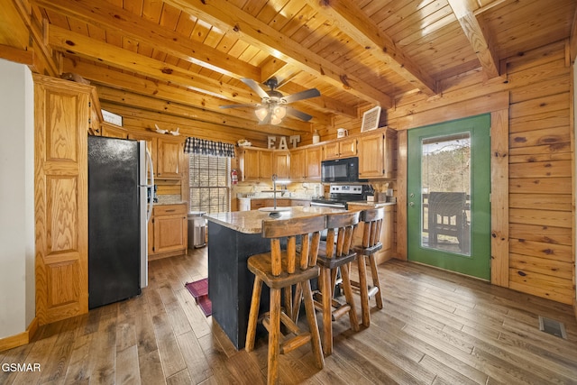 kitchen with hardwood / wood-style flooring, a kitchen island, visible vents, wood ceiling, and appliances with stainless steel finishes