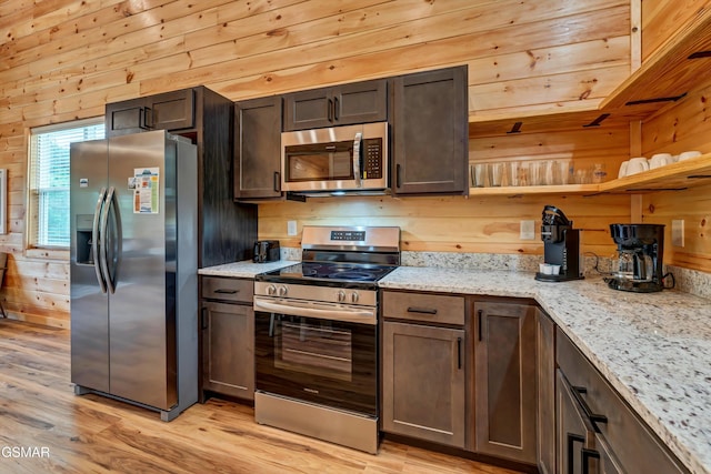 1014 Pinyon Cir, Pigeon Forge, TN 37863 - kitchen with stainless steel appliances, light wood-style flooring, wood walls, light stone counters, and dark brown cabinets