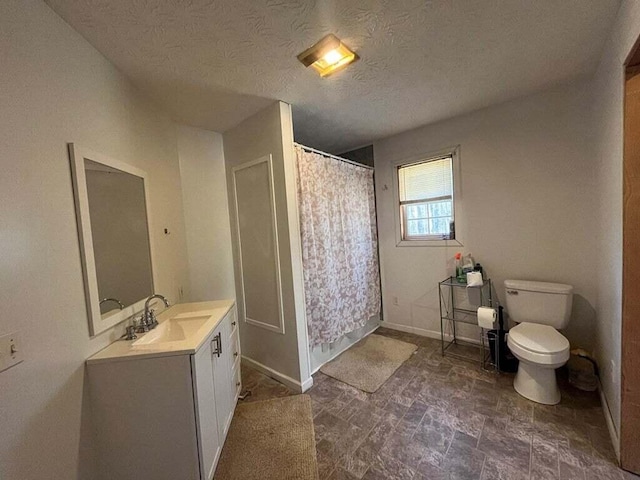 bathroom featuring vanity, a textured ceiling, and toilet