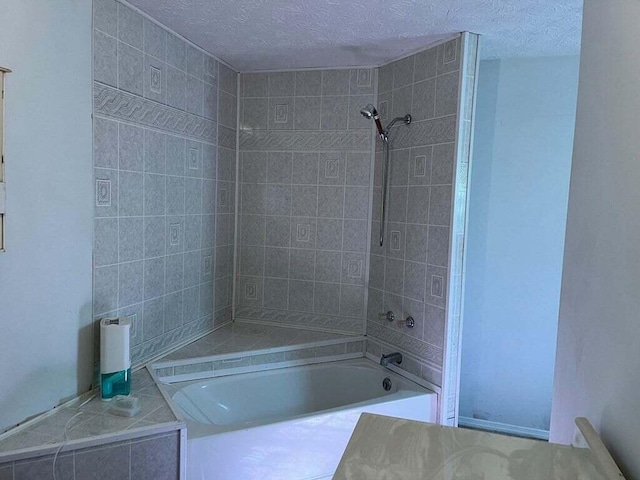 bathroom featuring a textured ceiling and tiled shower / bath