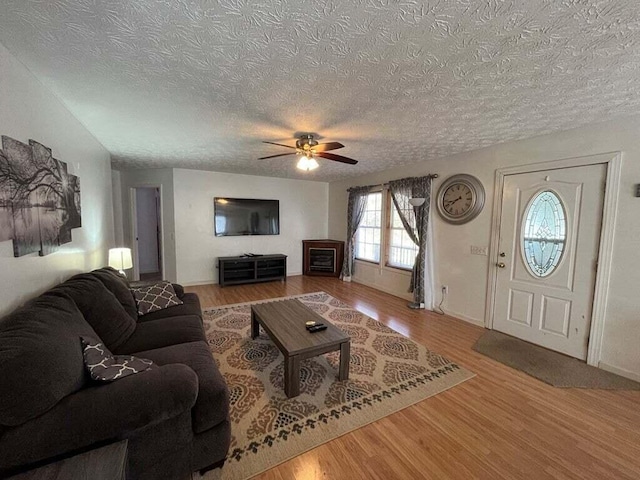 living room with hardwood / wood-style flooring, ceiling fan, and a textured ceiling