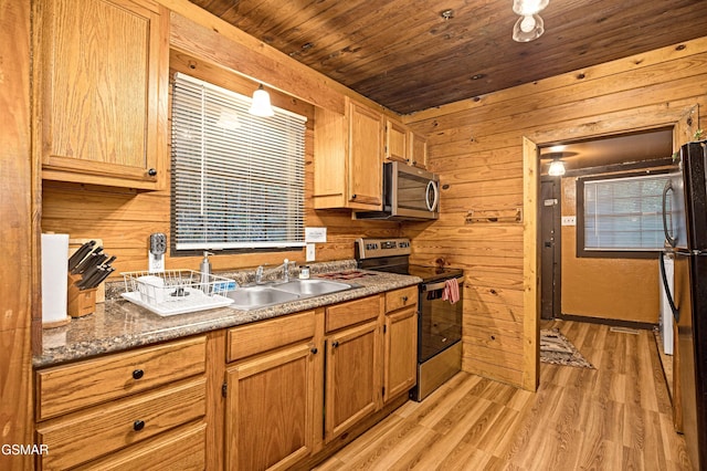 kitchen with wood ceiling, wooden walls, sink, and stainless steel appliances