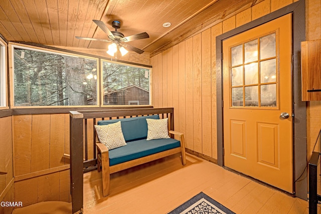 living area featuring wood walls, ceiling fan, wooden ceiling, and lofted ceiling