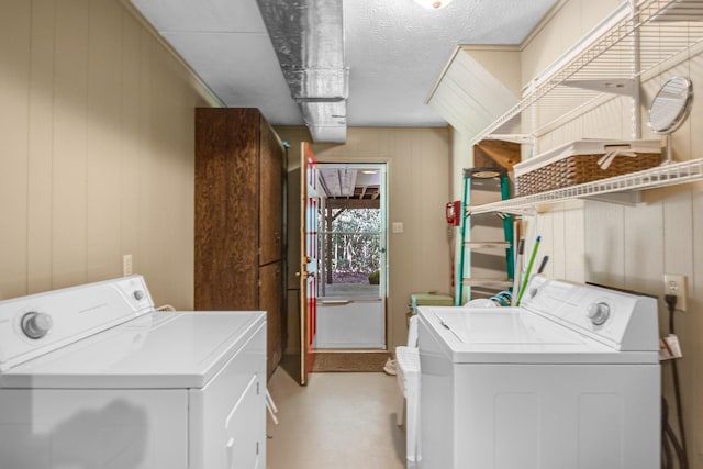 washroom with washing machine and dryer, wood walls, and a textured ceiling