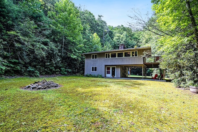 back of property with a lawn, a patio area, and a wooden deck