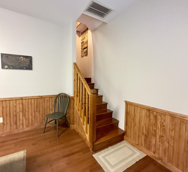 staircase with hardwood / wood-style floors and wooden walls