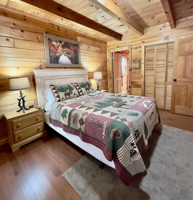 bedroom with dark wood-type flooring, beam ceiling, wooden ceiling, a closet, and wood walls