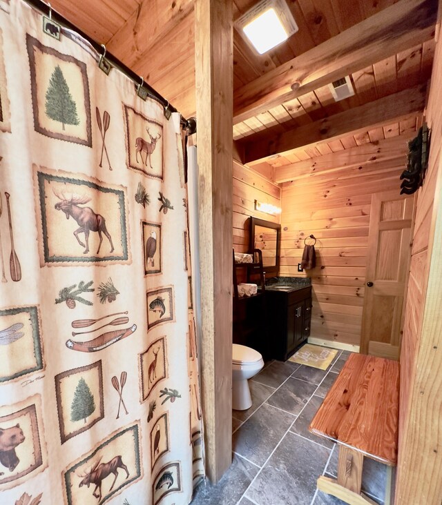 bathroom with wood ceiling, vanity, beam ceiling, toilet, and wood walls