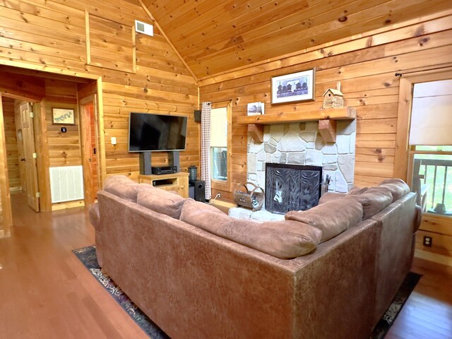 living room with hardwood / wood-style flooring, wood ceiling, a fireplace, and wooden walls