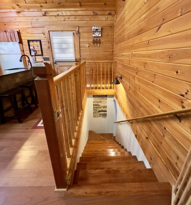 stairs with hardwood / wood-style floors, sink, and wood walls