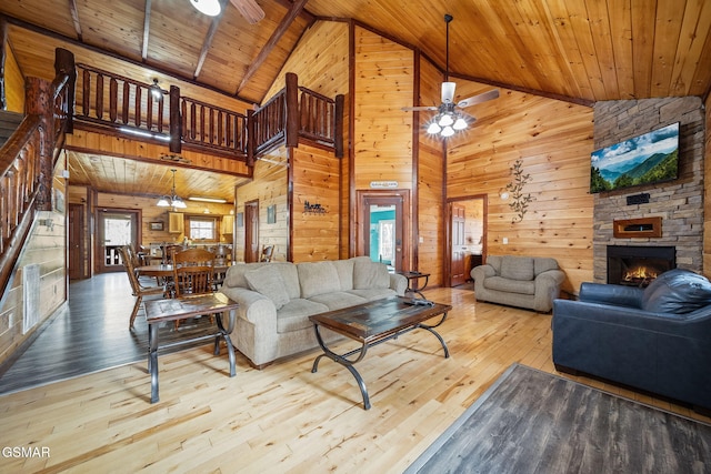 living room featuring high vaulted ceiling, wooden ceiling, wooden walls, and light hardwood / wood-style flooring