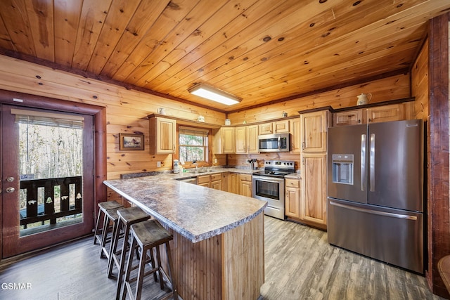 kitchen with stainless steel appliances, a breakfast bar area, wooden ceiling, and light hardwood / wood-style flooring