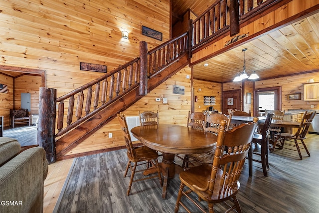 dining area with hardwood / wood-style flooring, a notable chandelier, wooden ceiling, and wooden walls