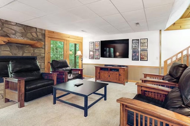 living room with a stone fireplace and light carpet