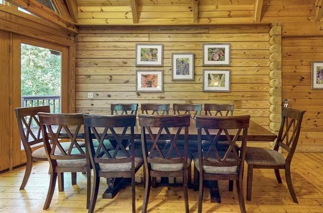 dining room featuring lofted ceiling with beams, light wood-type flooring, wooden walls, and wooden ceiling