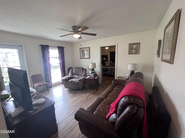 living room with a textured ceiling, a ceiling fan, and wood finished floors