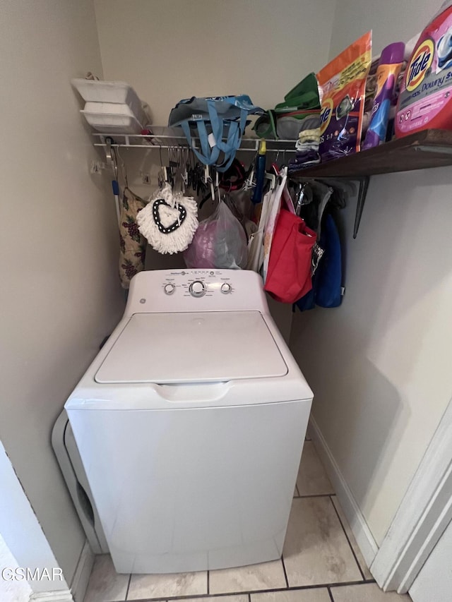 laundry area with light tile patterned floors, washer / dryer, and baseboards