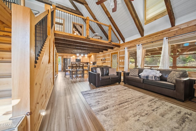 living room with high vaulted ceiling, wooden walls, ceiling fan, beam ceiling, and wood-type flooring