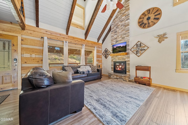 living room with high vaulted ceiling, ceiling fan, light wood-type flooring, a fireplace, and beamed ceiling