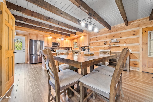 dining space with beamed ceiling and light hardwood / wood-style floors