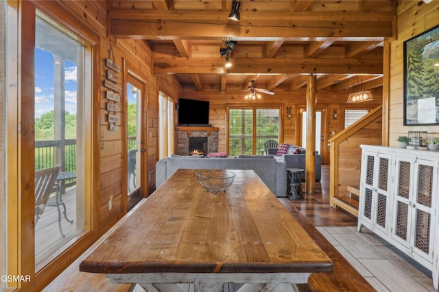 2083 Kerr Rd, Sevierville, TN 37876 - dining space with wood walls, wood ceiling, an outdoor stone fireplace, beamed ceiling, and a ceiling fan