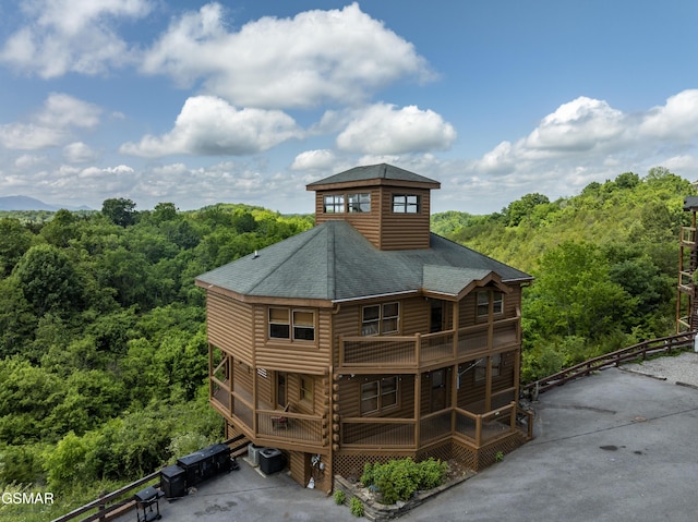 2083 Kerr Rd, Sevierville, TN 37876 - back of property featuring roof with shingles, a forest view, fence, log veneer siding, and central AC unit