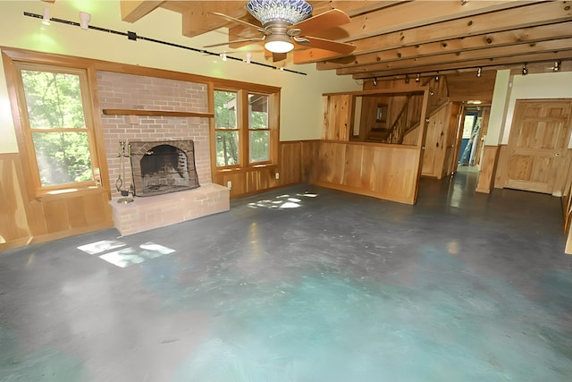 unfurnished living room featuring a wainscoted wall, concrete floors, plenty of natural light, and a brick fireplace