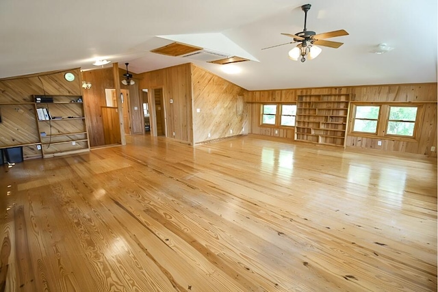 interior space with lofted ceiling, wood finished floors, a ceiling fan, and wooden walls