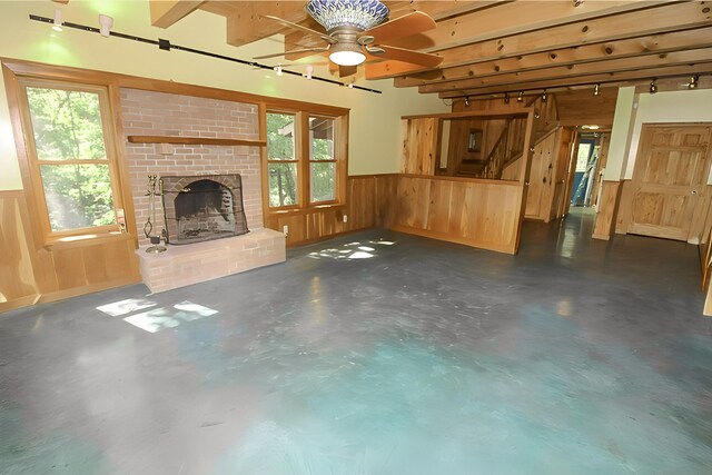 unfurnished living room with finished concrete flooring, a wainscoted wall, a fireplace, and a wealth of natural light