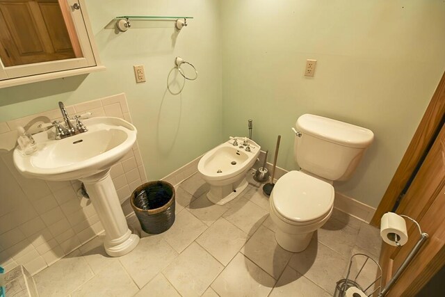 half bathroom with a bidet, toilet, and baseboards