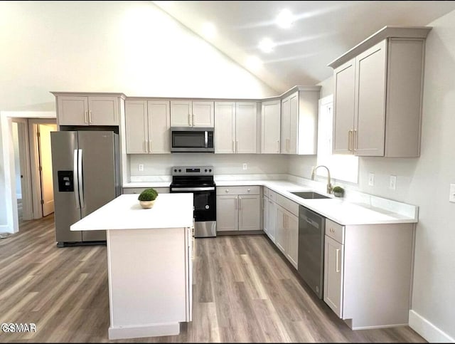 kitchen with sink, a center island, gray cabinets, appliances with stainless steel finishes, and hardwood / wood-style flooring