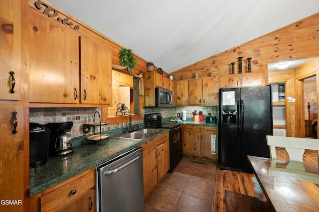 kitchen with sink, wooden walls, black appliances, decorative backsplash, and vaulted ceiling