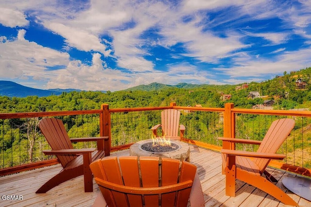wooden terrace featuring a fire pit, a wooded view, and a mountain view