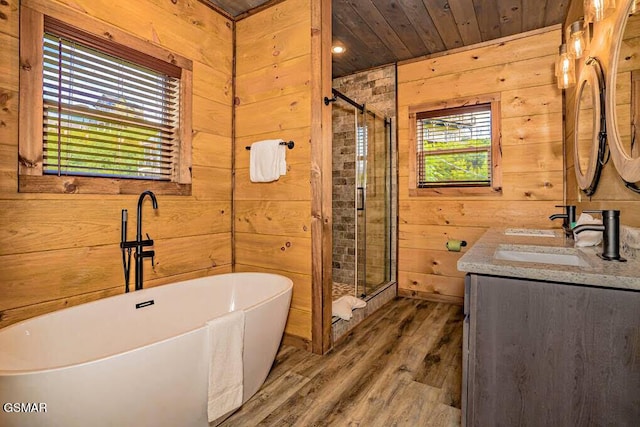 bathroom with a sink, wood walls, a stall shower, and wood finished floors