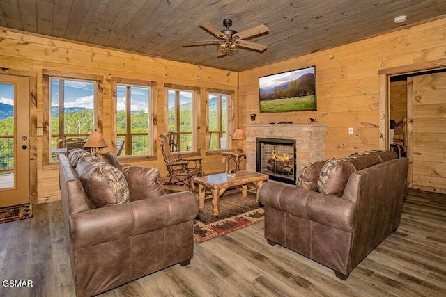 living area featuring ceiling fan, wooden walls, wooden ceiling, and wood finished floors
