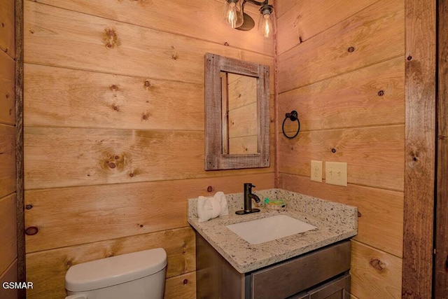 bathroom with toilet, vanity, and wooden walls