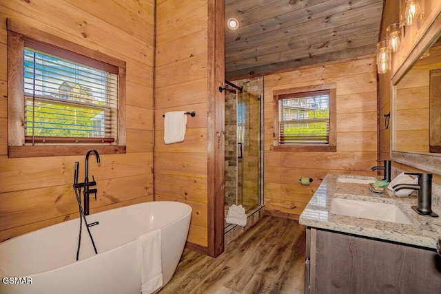 bathroom with a soaking tub, a sink, wood walls, and a stall shower