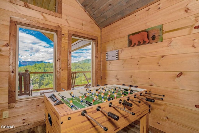 game room featuring wood ceiling, wood walls, a mountain view, and vaulted ceiling