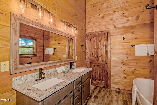 full bathroom with a sink, wood finished floors, wooden walls, and a freestanding bath