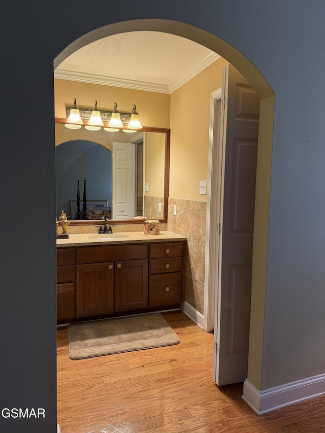 915 Fine Glen Dr, Sevierville, TN 37862 - bathroom featuring ornamental molding, wood finished floors, double vanity, tile walls, and wainscoting